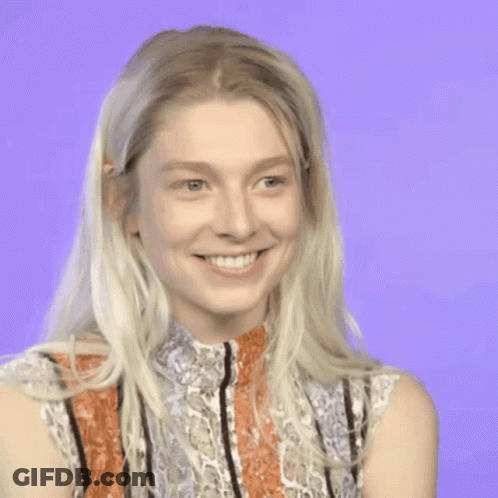 A Woman With Blonde Hair And A Striped Shirt Is Smiling GIF