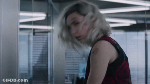 A Woman With Blonde Hair And A Tattoo On Her Arm Is Standing In A Room GIF