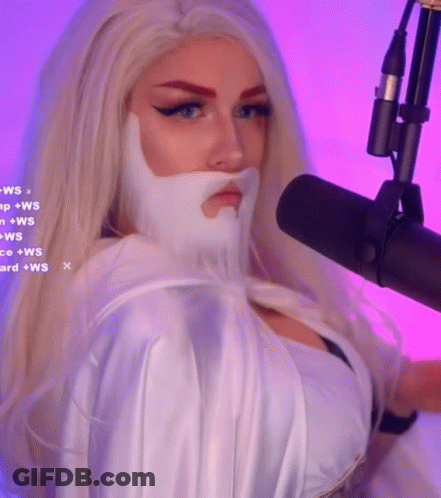 A Woman With Blonde Hair And A White Beard Is Standing In Front Of A Microphone GIF