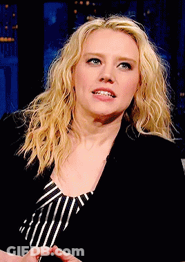 A Woman With Blonde Hair And Blue Eyes Is Wearing A Black Jacket And Striped Shirt GIF