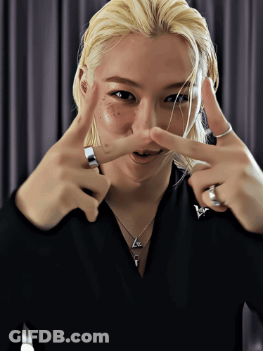 A Woman With Blonde Hair And Freckles Making A Peace Sign With Her Hands GIF