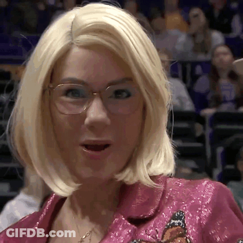 A Woman With Blonde Hair And Glasses Is Wearing A Pink Jacket With A Butterfly Embroidered On It GIF