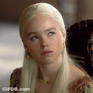 A Woman With Blonde Hair And Gold Earrings Looks To The Side GIF
