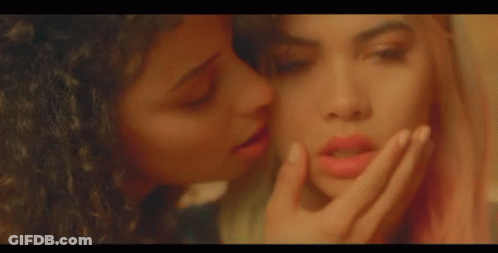 A Woman With Blonde Hair And Red Hair Is Sitting On A Bed With Her Eyes Closed . GIF