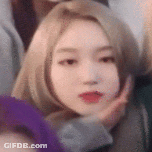 A Woman With Blonde Hair And Red Lips Is Making A Funny Face . GIF