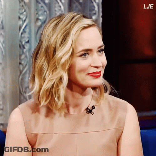 A Woman With Blonde Hair And Red Lips Is Sitting In Front Of A Microphone With The Letters Lje Above Her Head GIF