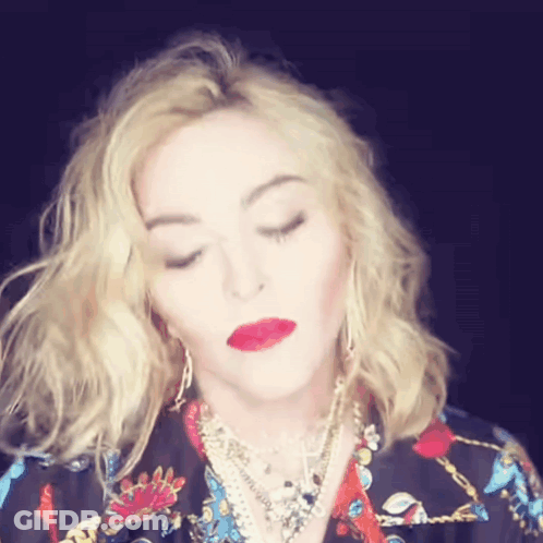 A Woman With Blonde Hair And Red Lips Is Wearing A Floral Shirt GIF