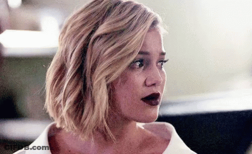 A Woman With Blonde Hair And Red Lips Is Wearing A White Shirt GIF