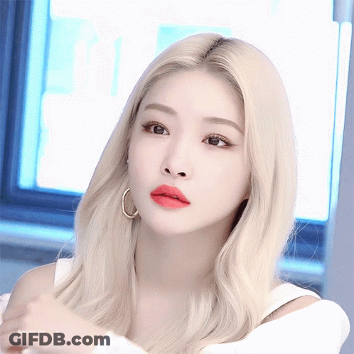 A Woman With Blonde Hair And Red Lips Is Wearing Hoop Earrings And A White Top GIF