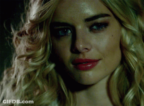 A Woman With Blonde Hair And Red Lips Looks At The Camera GIF