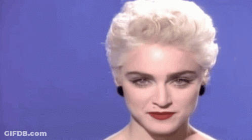 A Woman With Blonde Hair And Red Lipstick Is Looking At The Camera . GIF