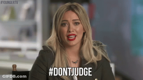 A Woman With Blonde Hair And Red Lipstick Is Sitting In A Chair And Saying `` Don 'T Judge '' . GIF