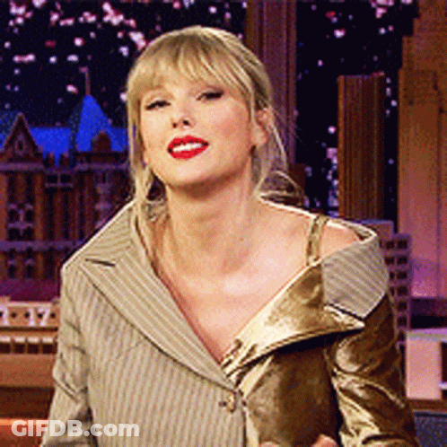 A Woman With Blonde Hair And Red Lipstick Is Wearing A Tan Striped Jacket GIF