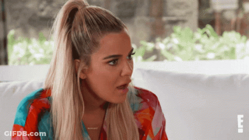 A Woman With Blonde Hair In A Ponytail Is Sitting On A Couch With The Letter E On The Bottom Right GIF