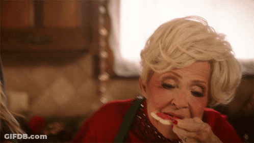 A Woman With Blonde Hair Is Eating A Piece Of Food GIF