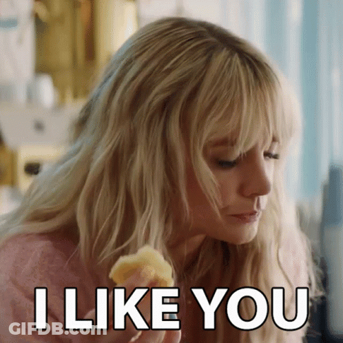 A Woman With Blonde Hair Is Eating A Piece Of Food And Says I Like You GIF