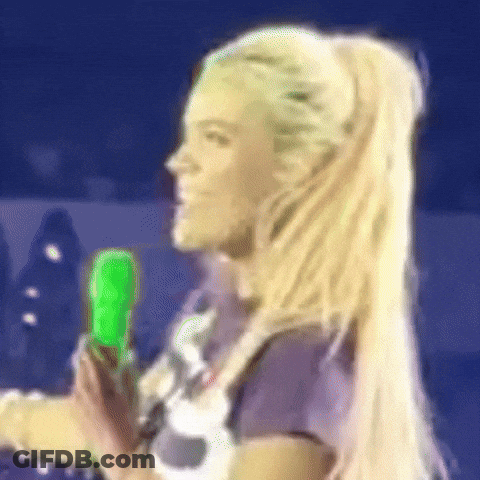 A Woman With Blonde Hair Is Holding A Green Object . GIF