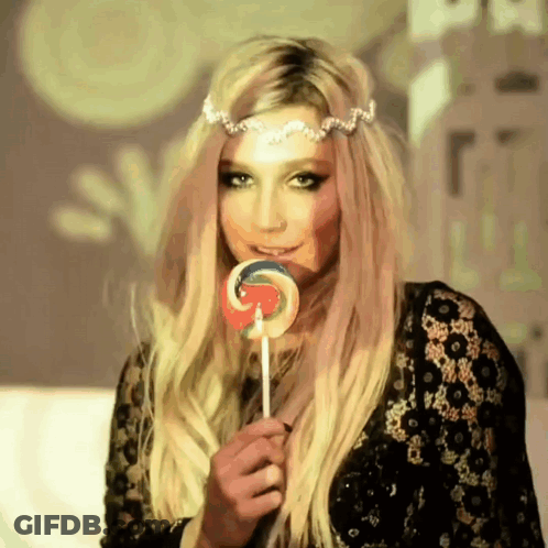 A Woman With Blonde Hair Is Holding A Lollipop In Her Hand GIF