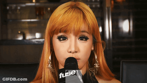 A Woman With Blonde Hair Is Holding A Microphone That Says Fuse GIF
