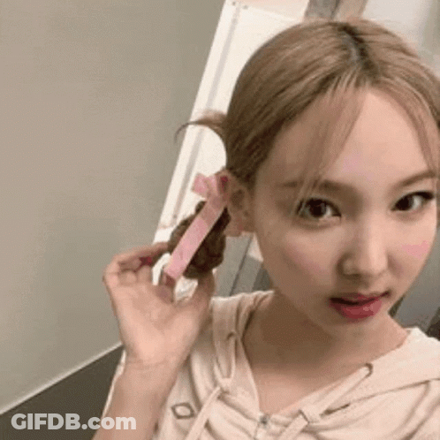 A Woman With Blonde Hair Is Holding A Pink Ribbon In Her Hair . GIF