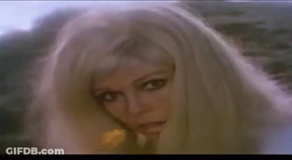 A Woman With Blonde Hair Is Holding A Yellow Flower In Her Hand . GIF