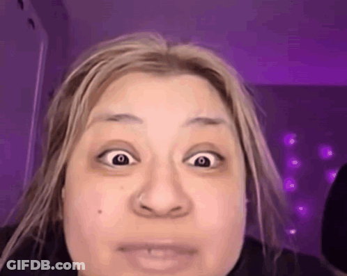 A Woman With Blonde Hair Is Making A Funny Face With Her Eyes Wide Open . GIF