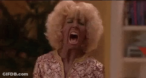 A Woman With Blonde Hair Is Screaming With Her Mouth Wide Open In A Room . GIF