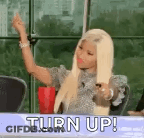 A Woman With Blonde Hair Is Sitting At A Table With A Red Cup In Her Hand . GIF