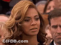 A Woman With Blonde Hair Is Sitting In A Crowd Of People . GIF