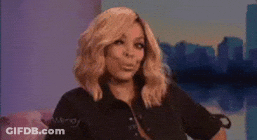A Woman With Blonde Hair Is Sitting On A Couch In Front Of A City Skyline . GIF