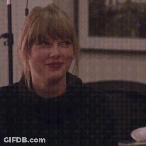 A Woman With Blonde Hair Is Smiling With Her Eyes Closed And Wearing A Black Sweater . GIF