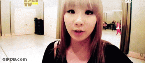 A Woman With Blonde Hair Is Standing In A Room With A Mirror . GIF