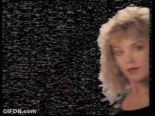 A Woman With Blonde Hair Is Standing In Front Of A Black Background With A Lot Of Static . GIF