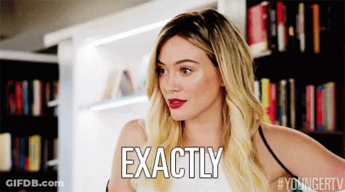 A Woman With Blonde Hair Is Standing In Front Of A Bookshelf And Says Exactly . GIF