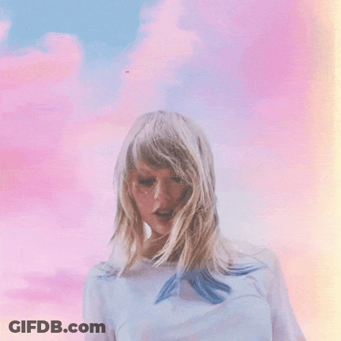 A Woman With Blonde Hair Is Standing In Front Of A Cloudy Sky GIF