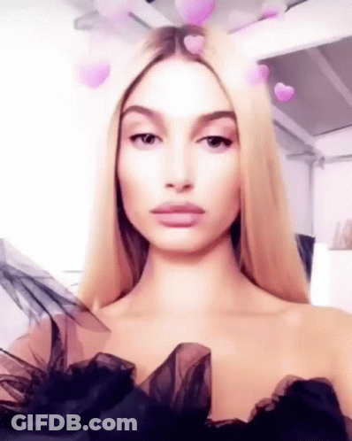 A Woman With Blonde Hair Is Wearing A Black Dress And Taking A Selfie . GIF