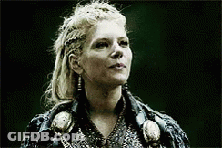 A Woman With Blonde Hair Is Wearing A Black Jacket And Earrings And Looking Up . GIF