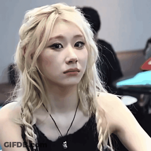 A Woman With Blonde Hair Is Wearing A Black Tank Top And A Black Necklace GIF