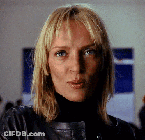 A Woman With Blonde Hair Is Wearing A Black Turtleneck And A Leather Jacket GIF