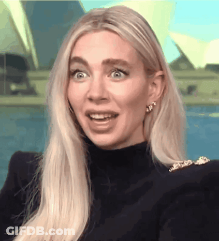 A Woman With Blonde Hair Is Wearing A Black Turtleneck And Gold Earrings GIF