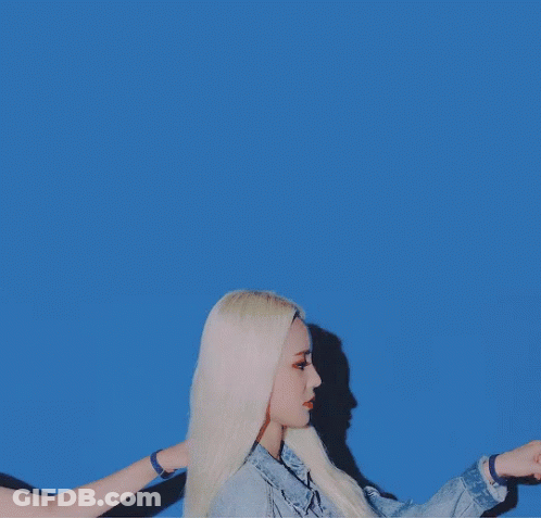 A Woman With Blonde Hair Is Wearing A Blue Denim Jacket GIF