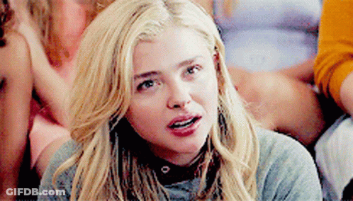 A Woman With Blonde Hair Is Wearing A Grey Sweater And Choker . GIF