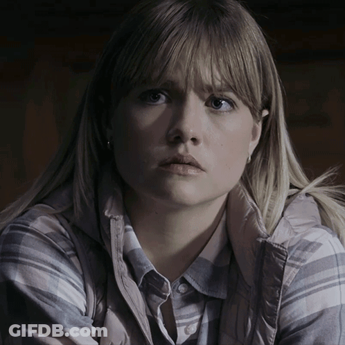 A Woman With Blonde Hair Is Wearing A Plaid Shirt And A Grey Vest GIF