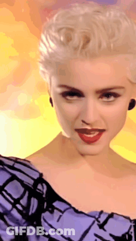 A Woman With Blonde Hair Is Wearing A Purple Dress GIF