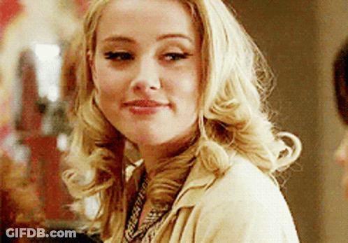 A Woman With Blonde Hair Is Wearing A Tan Jacket And A Necklace GIF
