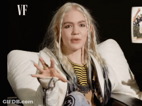 A Woman With Blonde Hair Is Wearing A White Jacket GIF