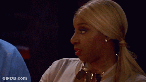 A Woman With Blonde Hair Is Wearing A White Shirt And Gold Necklace GIF