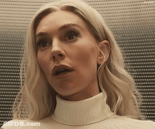 A Woman With Blonde Hair Is Wearing A White Turtleneck Sweater And Looking Surprised . GIF