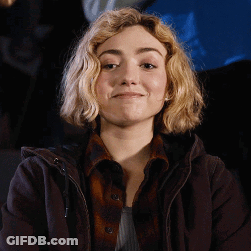 A Woman With Blonde Hair Wearing A Brown Jacket GIF