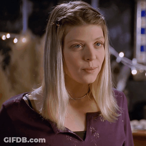A Woman With Blonde Hair Wearing A Purple Sweater GIF